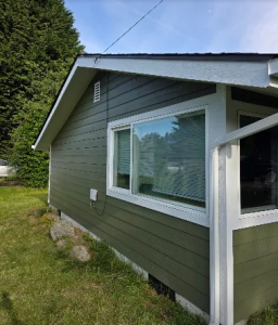 Exterior view of a residential home showcasing newly installed green siding and white trim by Final Touch Construction LLC.