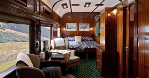 Private suite aboard Rovos Rail with double bed, armchairs and picture windows overlooking the landscape