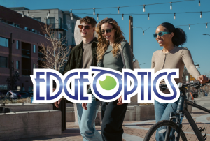 Three people in their 20's-30's smiling and walking in town with a bike wearing fashionable sunglasses