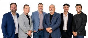 A composite group photo of six smiling male real estate professionals wearing blazers, standing against a plain white background.