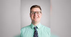 Headshot of Daniel Roth, a man with short hair and glasses wearing a light green dress shirt and a blue floral tie, smiling against a light gray backdrop.
