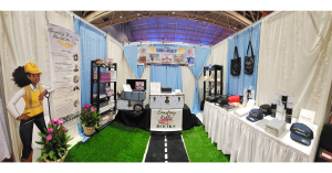 Panoramic view of the Courtney Kelly Books booth in the WeLoveUs Marketplace at Essence Festival 2026. Books and aviation-themed decor is seen along with a cutout of Celeste, the main character of the book.