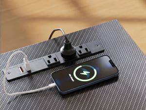 OffiGo electric standing desk with built-in power strip and USB charging station for phones and office devices.