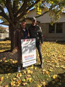 Davids & DeLaat, the #1 performing team of Niagara Region REALTORS® at REMAX Niagara Realty Ltd Shawn DeLaat standing with a sold sign at a Niagara home