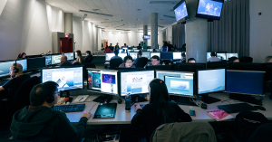 Students work at computer stations in a Vancouver Film School computer lab, with multiple monitors displaying digital artwork and animation projects.
