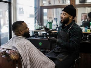 The Secret World app is expanding the role local businesses can play inside its creator community Local barber speaking with a customer inside a neighborhood barbershop connected to the Secret World creator community.