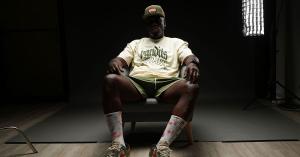man sitting in a chair wearing a hat, shorts and t-shirt at a photoshoot
