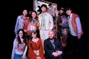 Producer Xingyun Zhao and members of The Inverted Realm cast and creative team pose together on stage around the production’s mirror set.