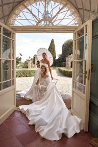 Two models wearing ivory OKSANA MUKHA bridal gowns in an ornate historic Tuscan setting.