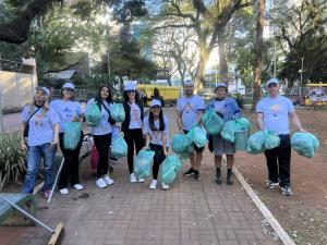 Volunteers in Plushie Planet caps holding green cleanup bags in a Brazilian park