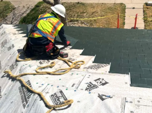 JM Roofing and Construction contractor in safety gear installing residential roof shingles on a home in El Paso, Texas.