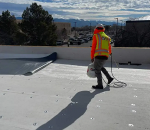 JM Roofing and Construction specialist applying professional roof coating solutions on a commercial flat roof in El Paso, Texas.