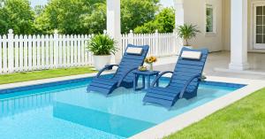 AquaCurve blue in-pool lounge chairs with a matching side table arranged on a shallow pool ledge in a backyard setting.
