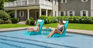 AquaCurve turquoise pool loungers with a matching side table on a shallow sun shelf while a mother and child relax in a backyard pool.