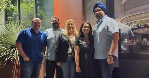 Five BARE International team members standing together in an indoor setting.