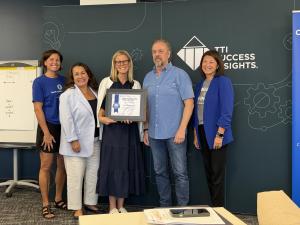 A group of people stand and accept a Blue Zones certification awarded to TTI Success Insights.