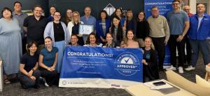 The TTI team stands with a Blue Zones banner to celebrate.