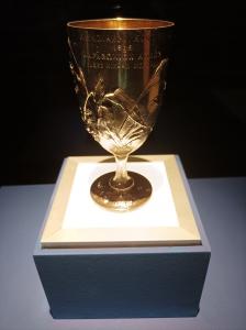 Gros plan sur la Coupe de Bréal de 1896, en argent pur, un trophée olympique de 15 centimètres de haut orné de reliefs Art Nouveau représentant oiseaux et plantes de Marathon, en Grèce.