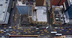 On September 10, 2026 — World Suicide Prevention Day — Raise the Rail, Inc Aerial view straight down onto a busy NYC intersection, taken from an unguarded rooftop edge.