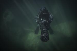 Spezialkräfte-Taucher mit Unterwasser-Scooter in dunklem Wasser bei eingeschränkter Sicht.