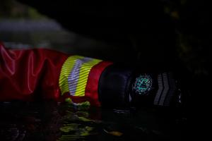 Leuchtende Luminox Uhr an einem behandschuhten Handgelenk bei Dunkelheit; Zeiger und Stundenmarkierungen sind deutlich sichtbar.