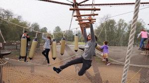 Sonoma Zipline Adventures is pleased to announce the addition of the brand new Redwood Aerial Adventure, anticipated to open Spring 2027 a boy reaches for rungs on a traverse element within an enclosed net for kids adventure course