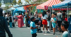 Families and children gather among Adriana’s Insurance tents and community booths at an outdoor Back-to-School event.