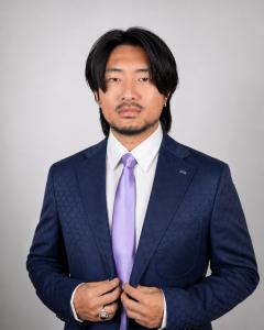 Professional portrait of Kaixiong Zhang, founder of Secret World app, wearing a navy Louis Vuitton suit and lavender tie.
