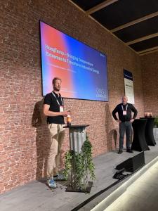 Two people are standing on stage with Enerin COO, Ralph Groen, in the centre seen pitching the technology with Enerin Co-founder and Head of Concept Design, Trond-Atle Asphjell, (standing on the right side of the stage) to a full room of the expert jury a