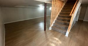 Light wood flooring at the base of a basement staircase.