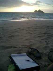 A legal pad and pen on the sand at sunrise, Lanikai Beach, Oahu, where H2ONU was written