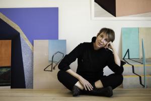 A photographer sitting on the floor in front of several colorful and contemporary, architectural photographs