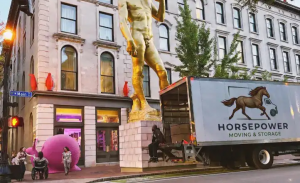 Horsepower Moving and Storage truck parked on Main Street beside a large gold statue in downtown Louisville.