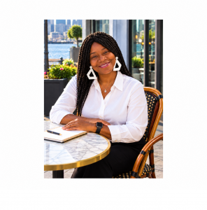 Zainab M. Lee, President & CEO of Lee Enterprise Ventures, LLC, seated at an outdoor table in a professional portrait.