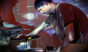 an impressionistic photo of a young man leaning over his recording gear