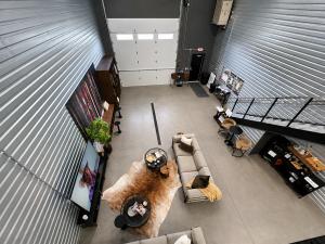 Interior of a micro-bay flex space looking down from a mezzanine at a couch and a tv