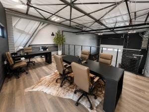 Interior of a micro-bay flex space on the mezzanine level where there is a custom office with a desk and chairs set up