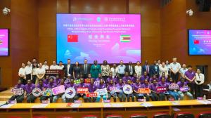 Zimbabwean students in purple shirts holding signs on stage with officials at the closing ceremony of the China-Africa Applied Talents Joint Teaching Programme at Ningbo Polytechnic University