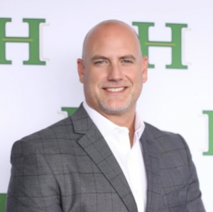 Headshot of Gabriel “Gabby” Dieppa, Managing Partner at Hotaling Insurance Services, wearing a gray suit jacket in front of a Hotaling-branded backdrop.