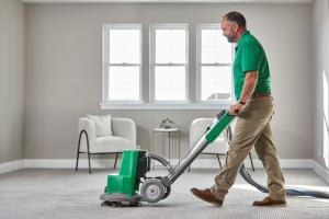 Professional carpet cleaner using Chem-Dry equipment in a Calgary bedroom