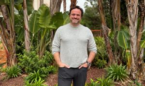 Portrait of Cristóvão Lopes, Owner and Interim General Manager of Falésia Hotel, standing outdoors among lush tropical greenery in the Algarve.