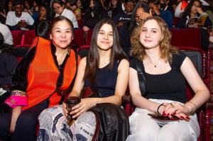 Three EduHam attendees seated together inside a theater, with other students seated in rows behind them.