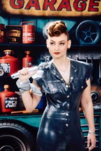 Singer-songwriter Ashley Ann in a vintage garage set, holding a chrome wrench.