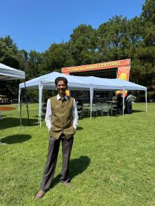 Hiten Bhuta standing at Atlanta India Festival 2026 in Roswell, Georgia, with the festival stage and outdoor event area in the background.