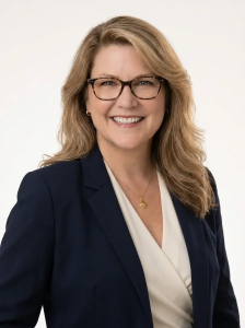 Woman with blond hair, glasses in blue blazer and white v-neck wrap around shirt