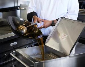 Employees straining used cooking oil into a designated collection container