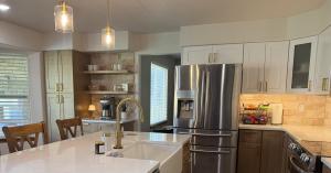 Kitchen remodel in Westminster, CO with a white quartz island, farmhouse sink, brass faucet, and two-tone shaker cabinets