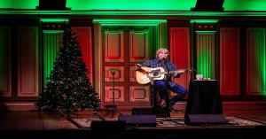 John Denver Christmas Tribute promotional photo featuring lead performer Rick Schuler in festive holiday concert branding.