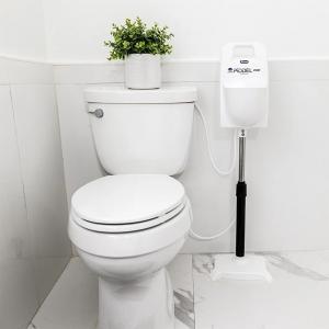 White PIDDÈL Pro™ height-adjustable Home Urinal System positioned beside an existing toilet in a residential bathroom.