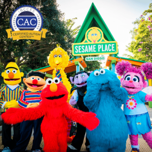 Sesame Street characters pose at Sesame Place San Diego’s entrance, with an autism-certified center sign visible.